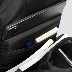 Close-up of a black backpack with a laptop compartment and various items inside.