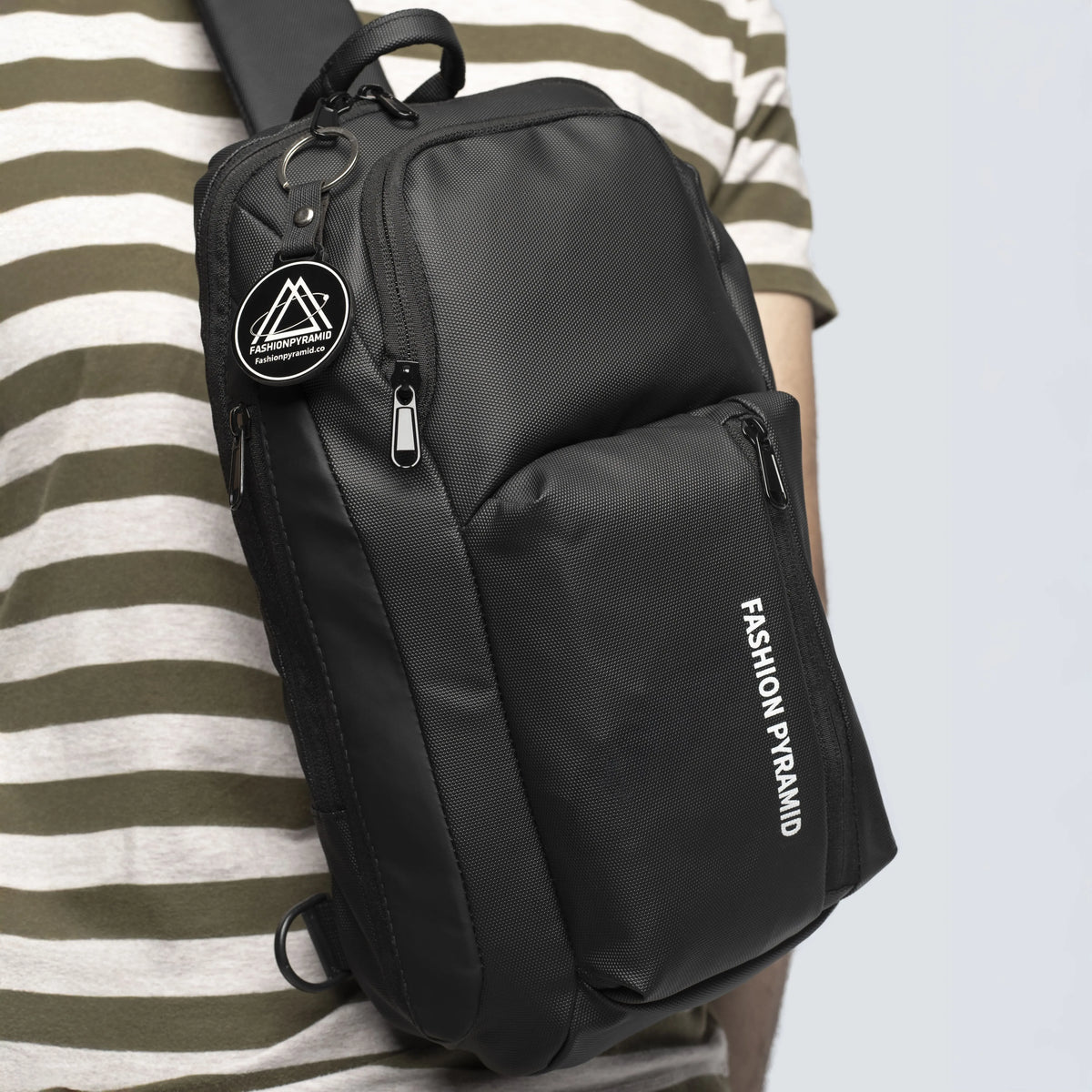Black sling bag with 'Fashion Pyramid' branding worn by a person in a striped shirt.