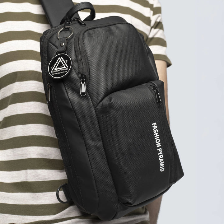Black sling bag with 'Fashion Pyramid' branding worn by a person in a striped shirt.