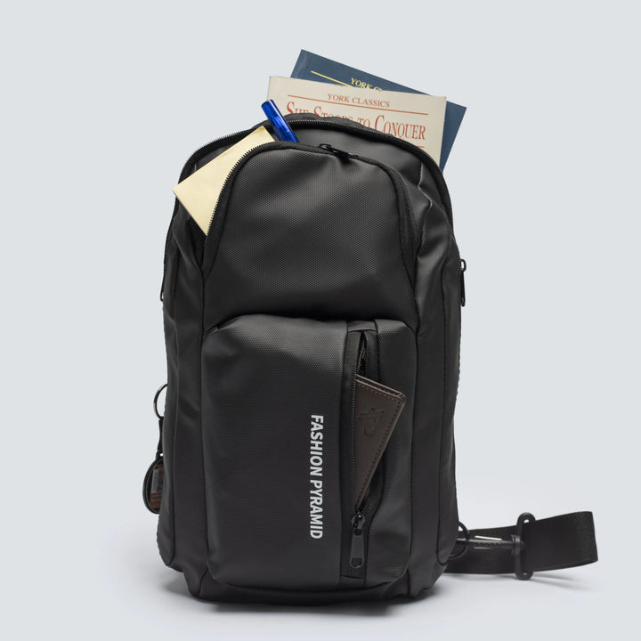 Black backpack with books and a pen on a light gray background