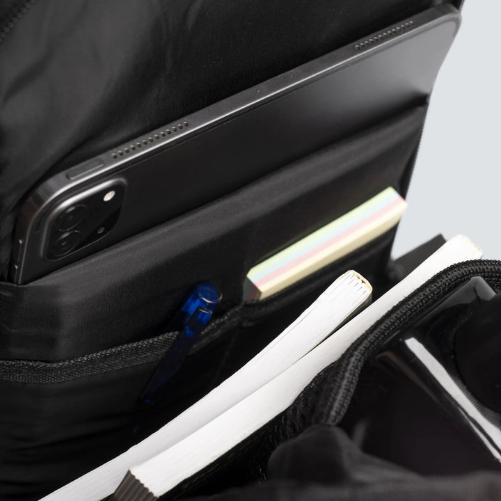 Close-up of a black backpack with a laptop compartment and various items inside.
