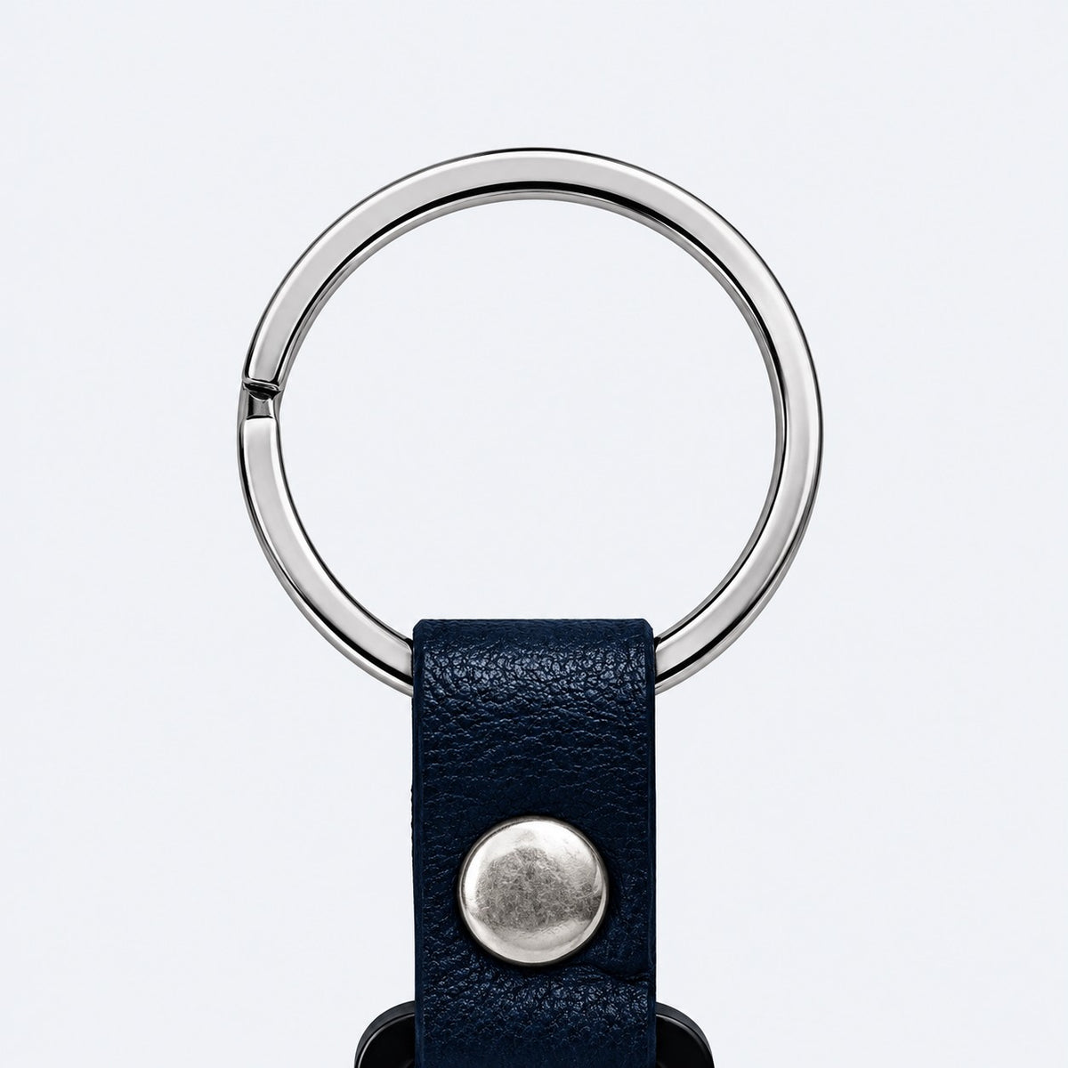 Close-up of the Safe Code bag tag's metal split ring and navy snap-button strap