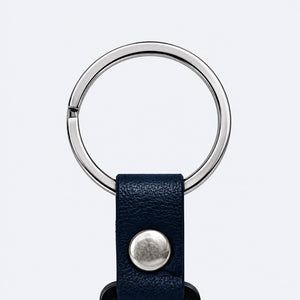 Close-up of the Safe Code bag tag's metal split ring and navy snap-button strap